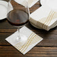 White linen-feel cocktail napkin with gold waves print.