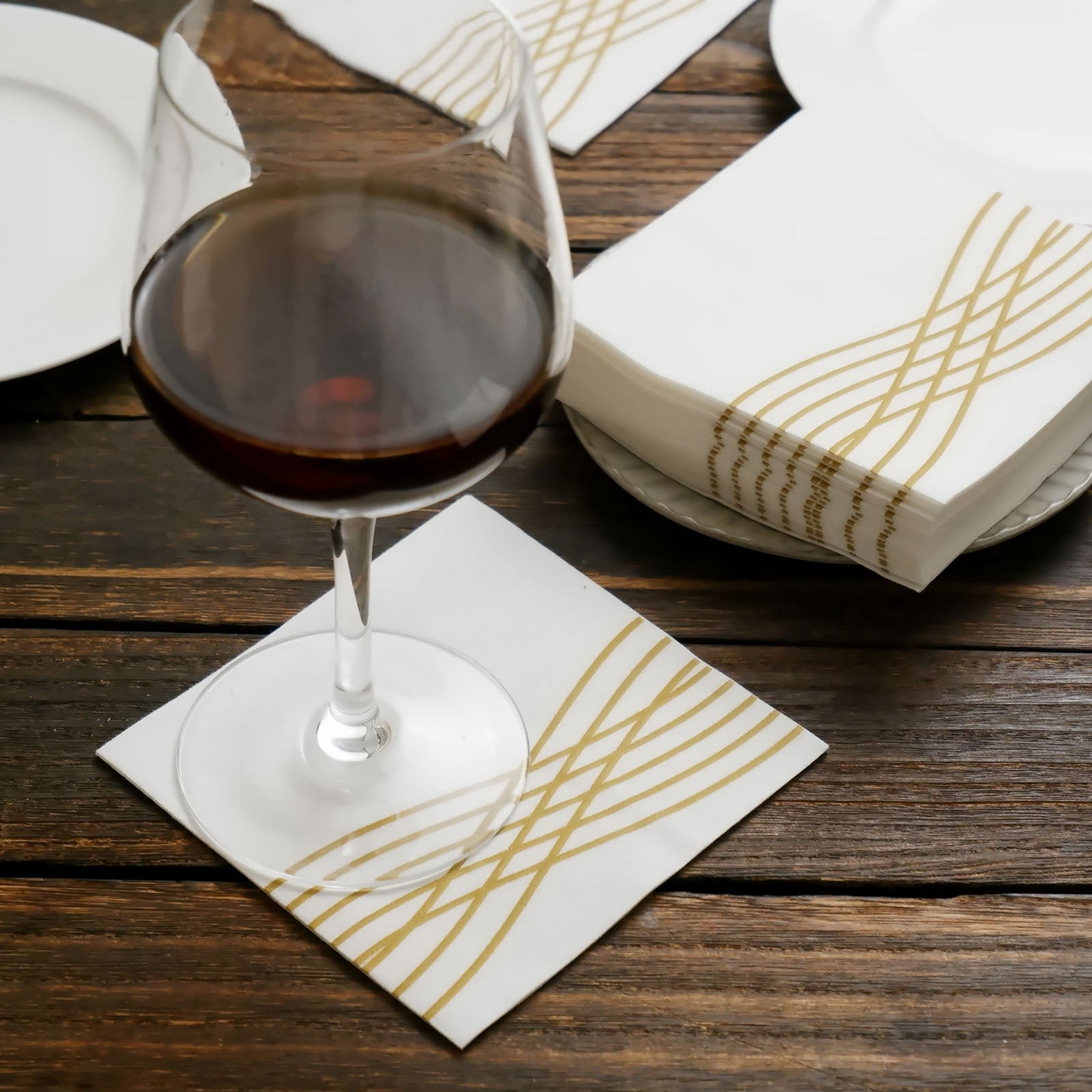 White linen-feel cocktail napkin with gold waves print.