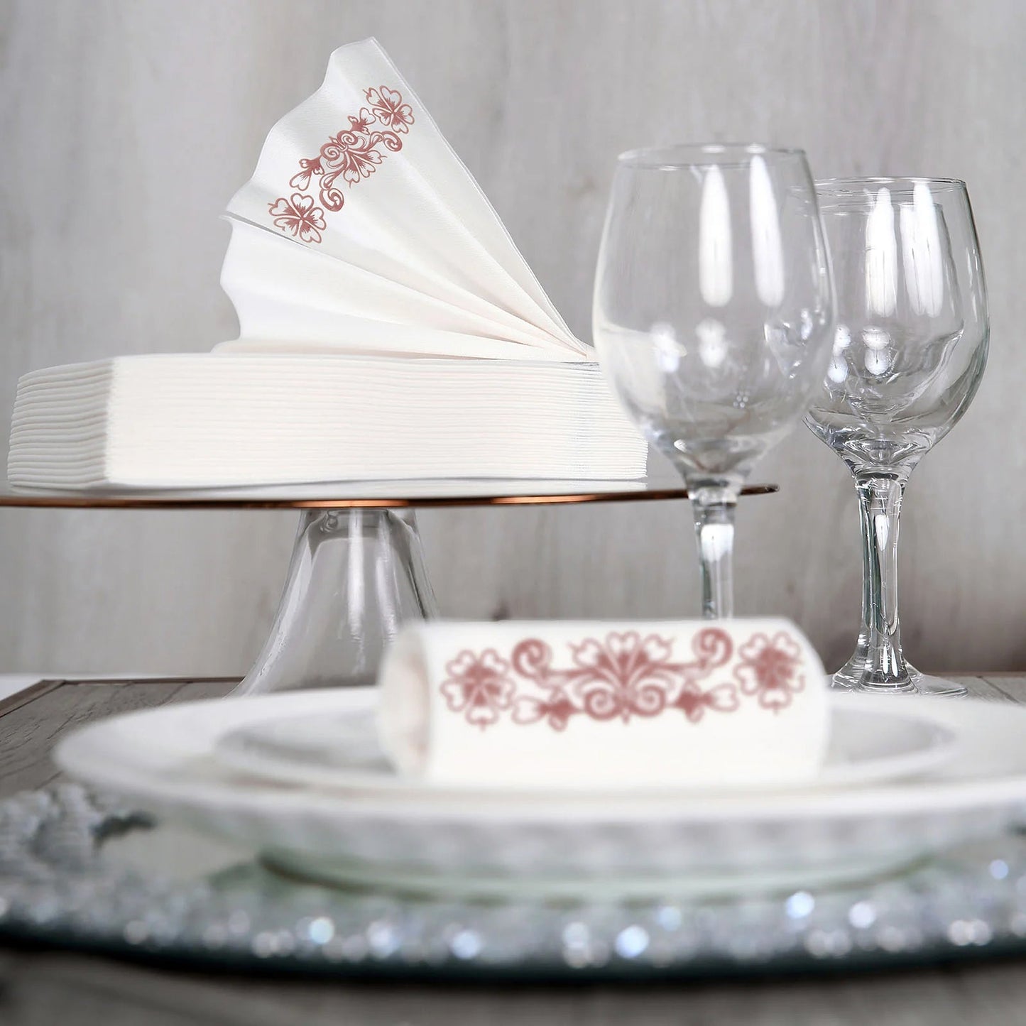 White linen-feel napkins with rose gold floral print on a dining table.