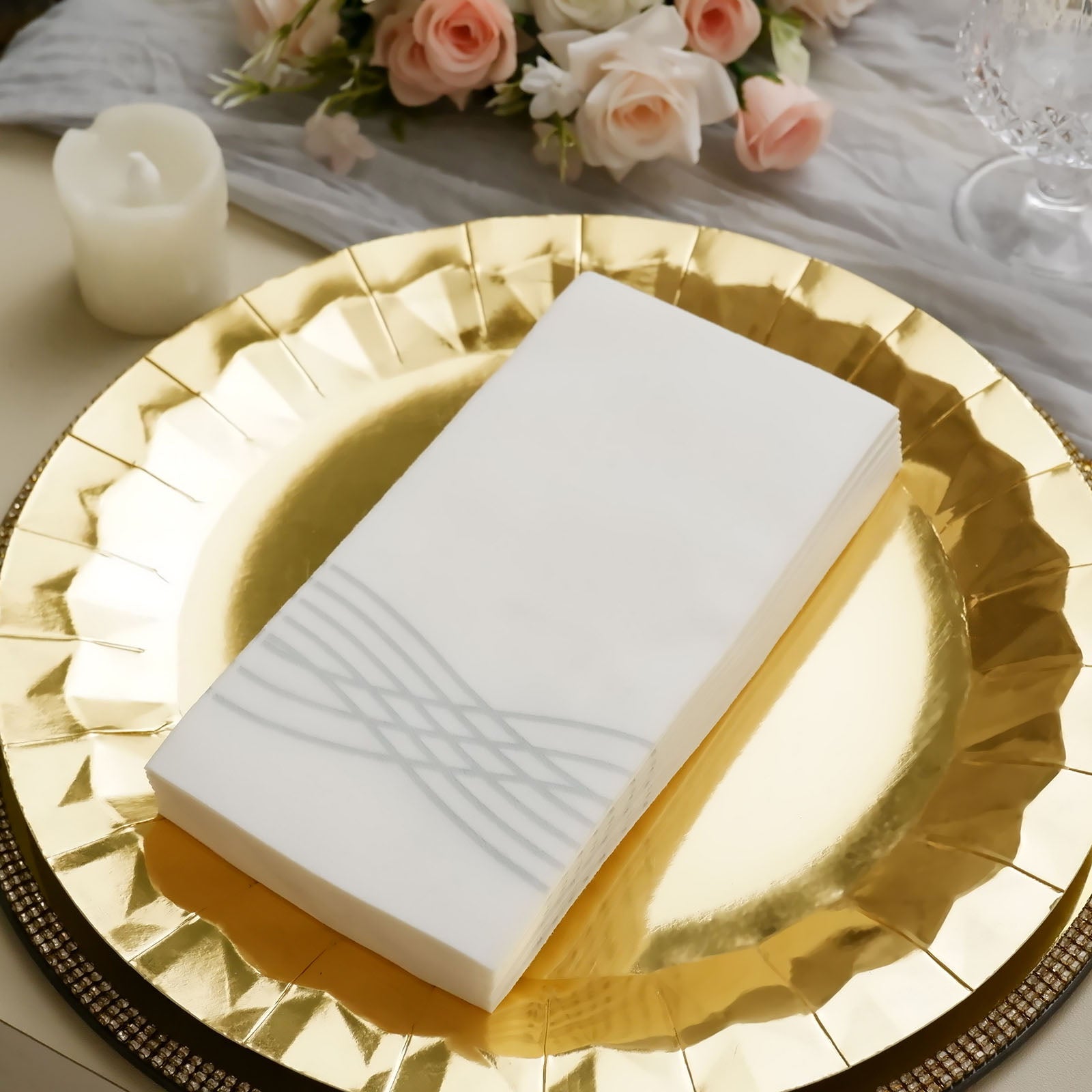 White linen-feel paper napkins with silver waves print on a gold plate.