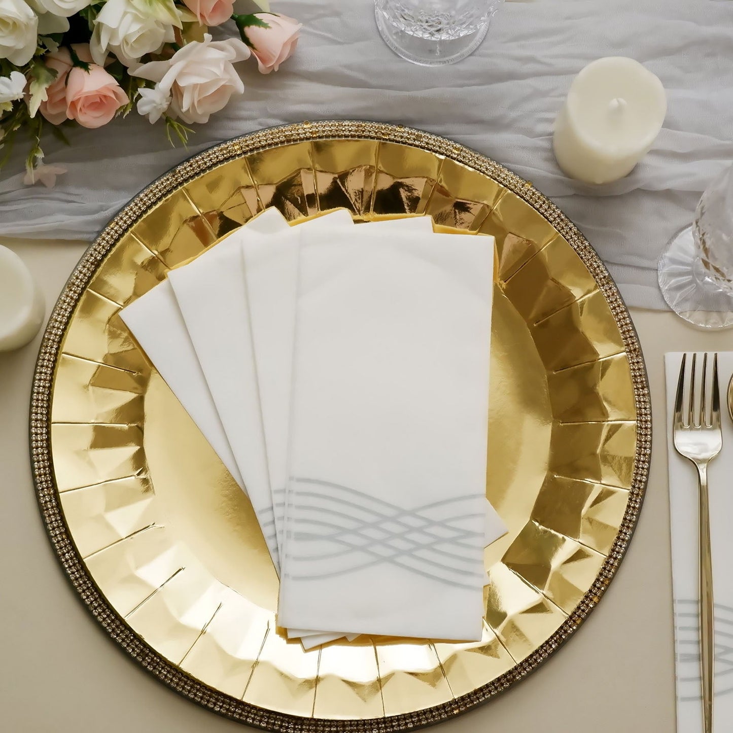 White linen-feel napkins with silver waves on a gold plate.