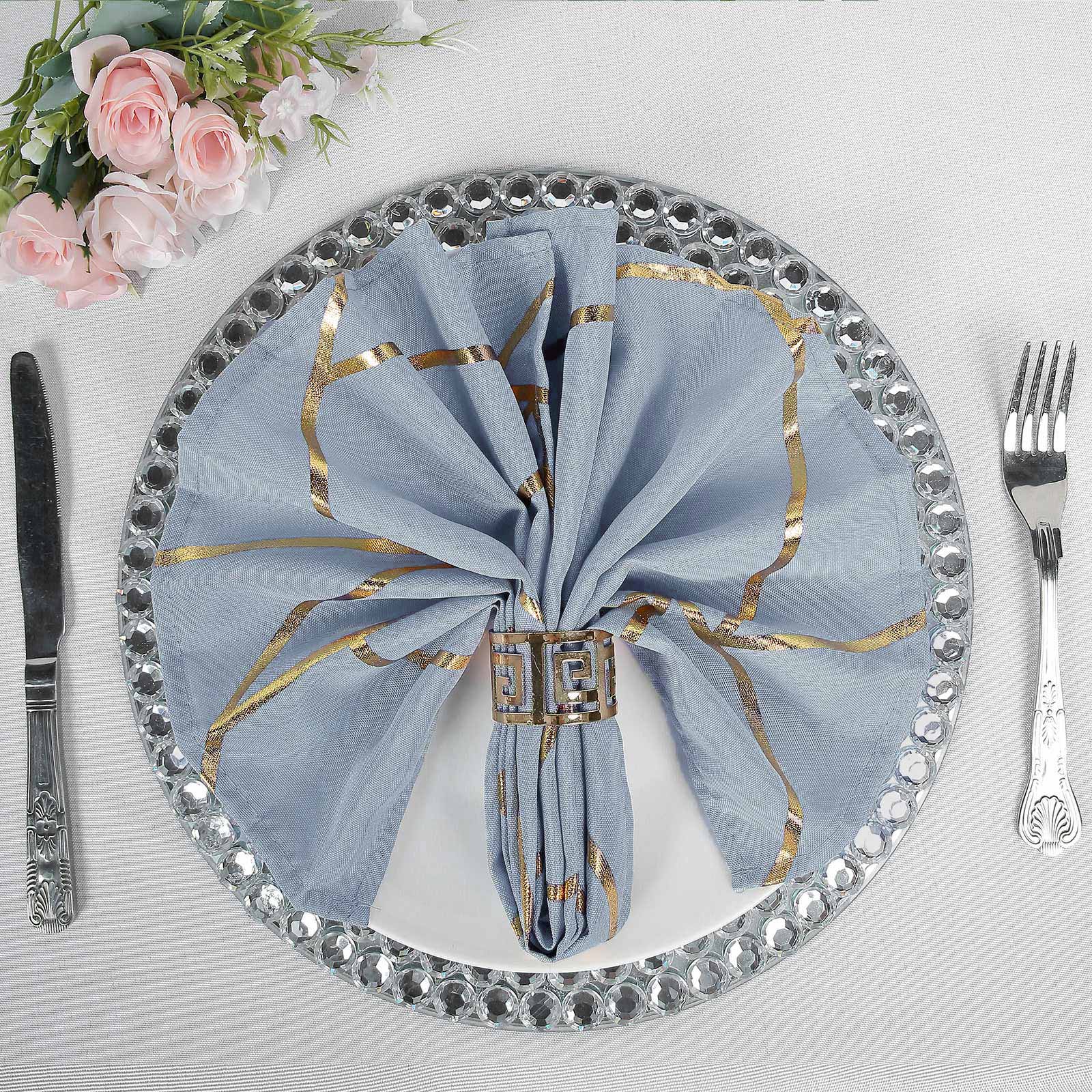 Modern dusty blue and geometric gold cloth dinner napkin on elegant table setting.