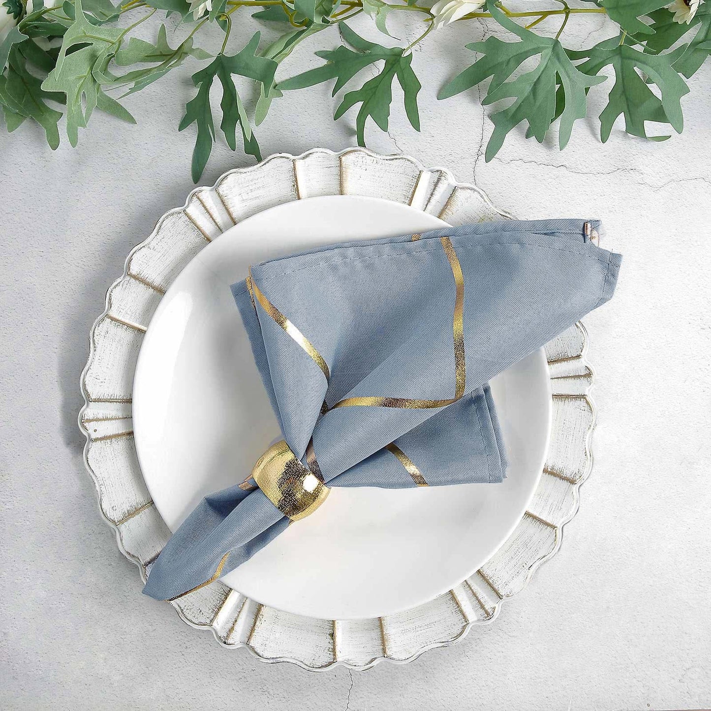 Modern dusty blue and geometric gold cloth dinner napkin on a plate.
