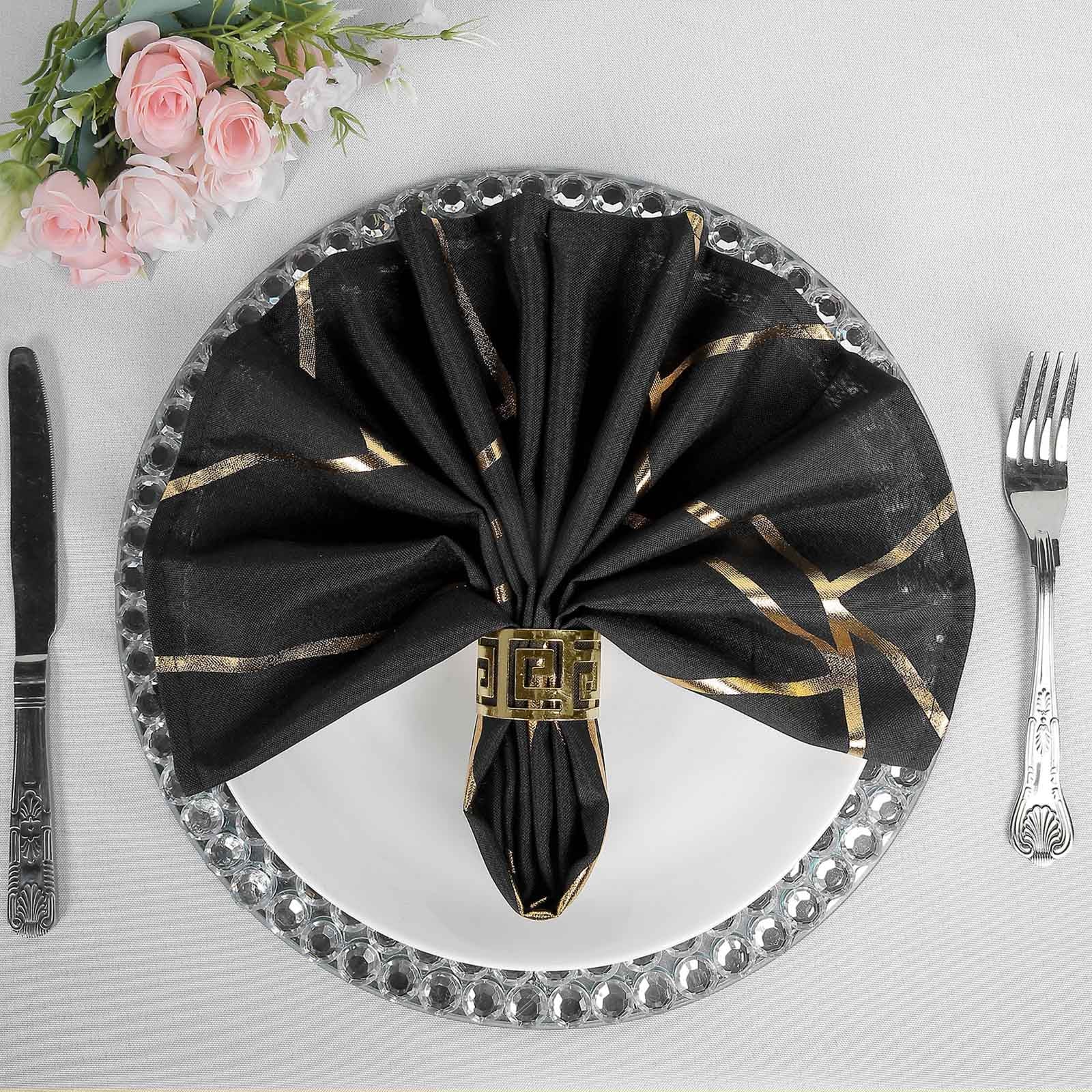 Modern black and geometric gold dinner napkin on a silver plate.