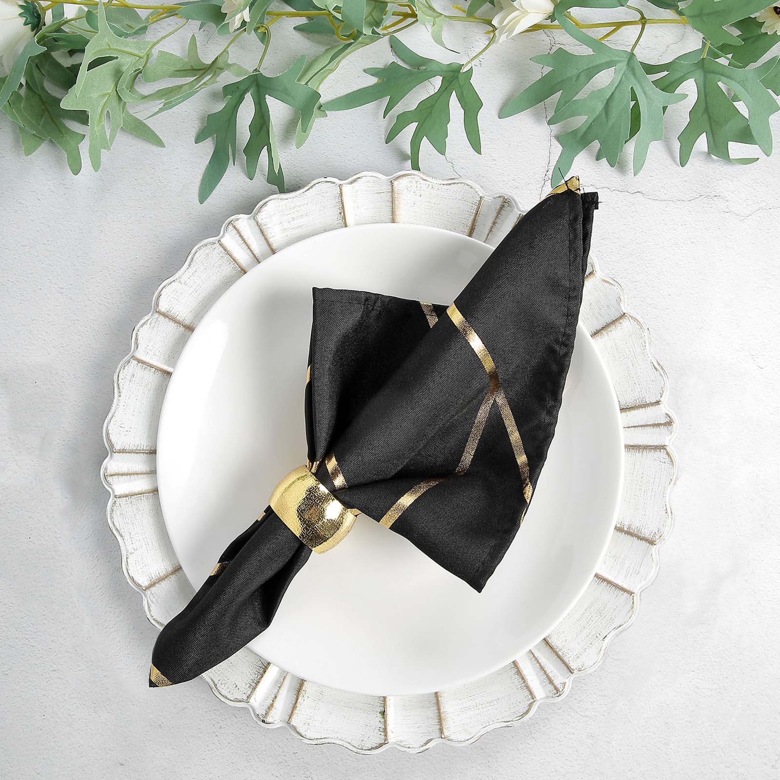 Modern black and gold geometric cloth dinner napkin on a white plate.
