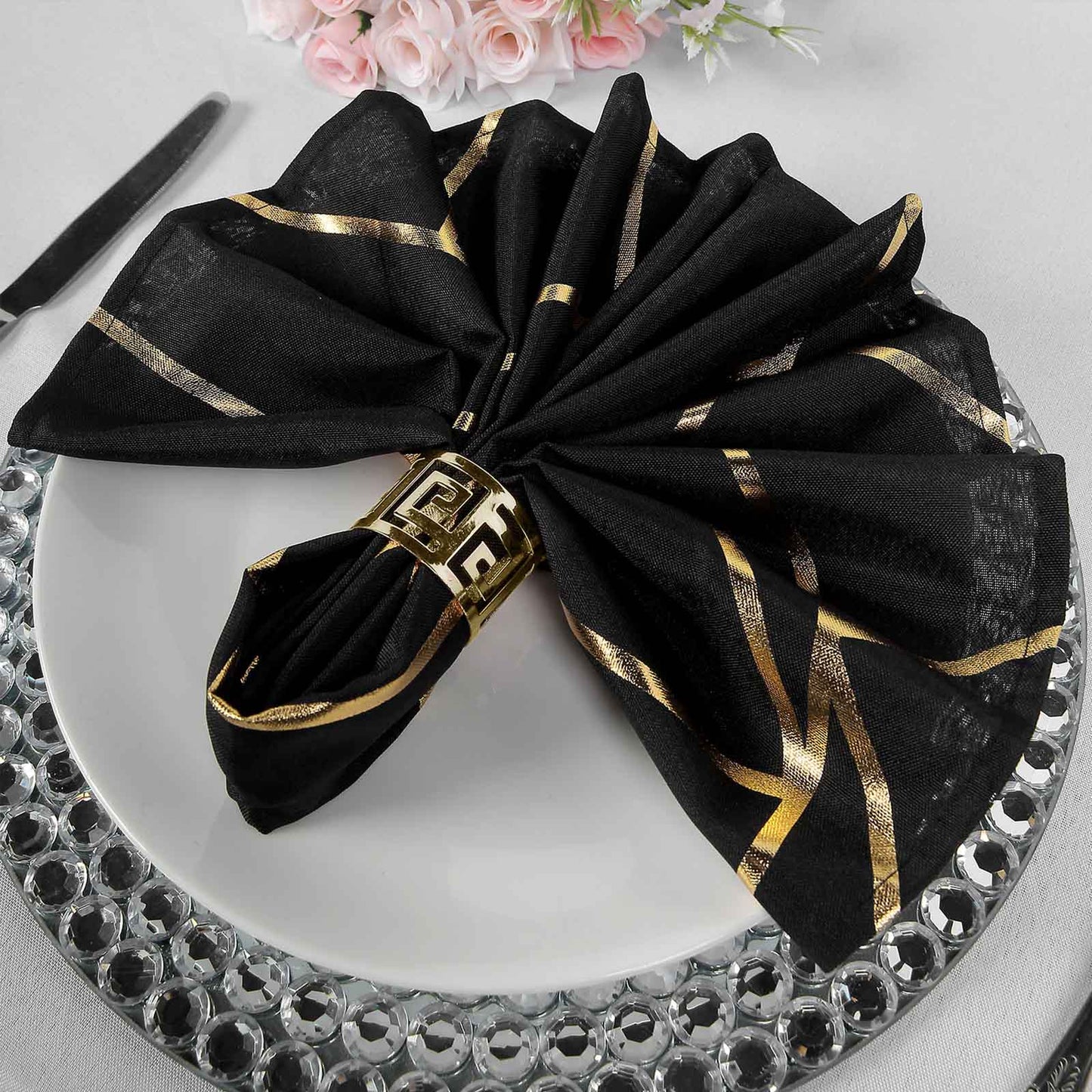 Black and gold geometric cloth dinner napkin set on a plate.