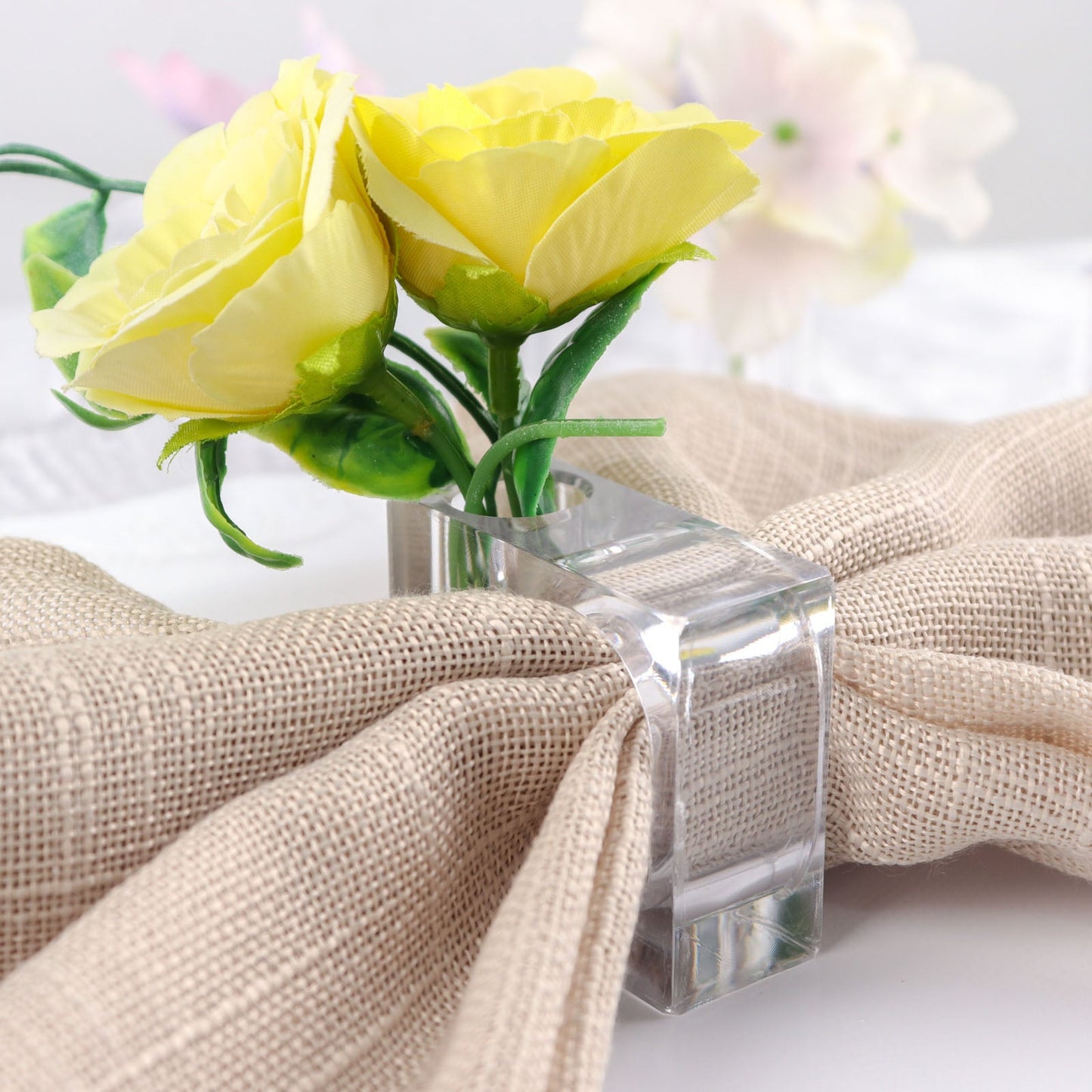 Clear acrylic square mini bud vase napkin ring with yellow flowers.