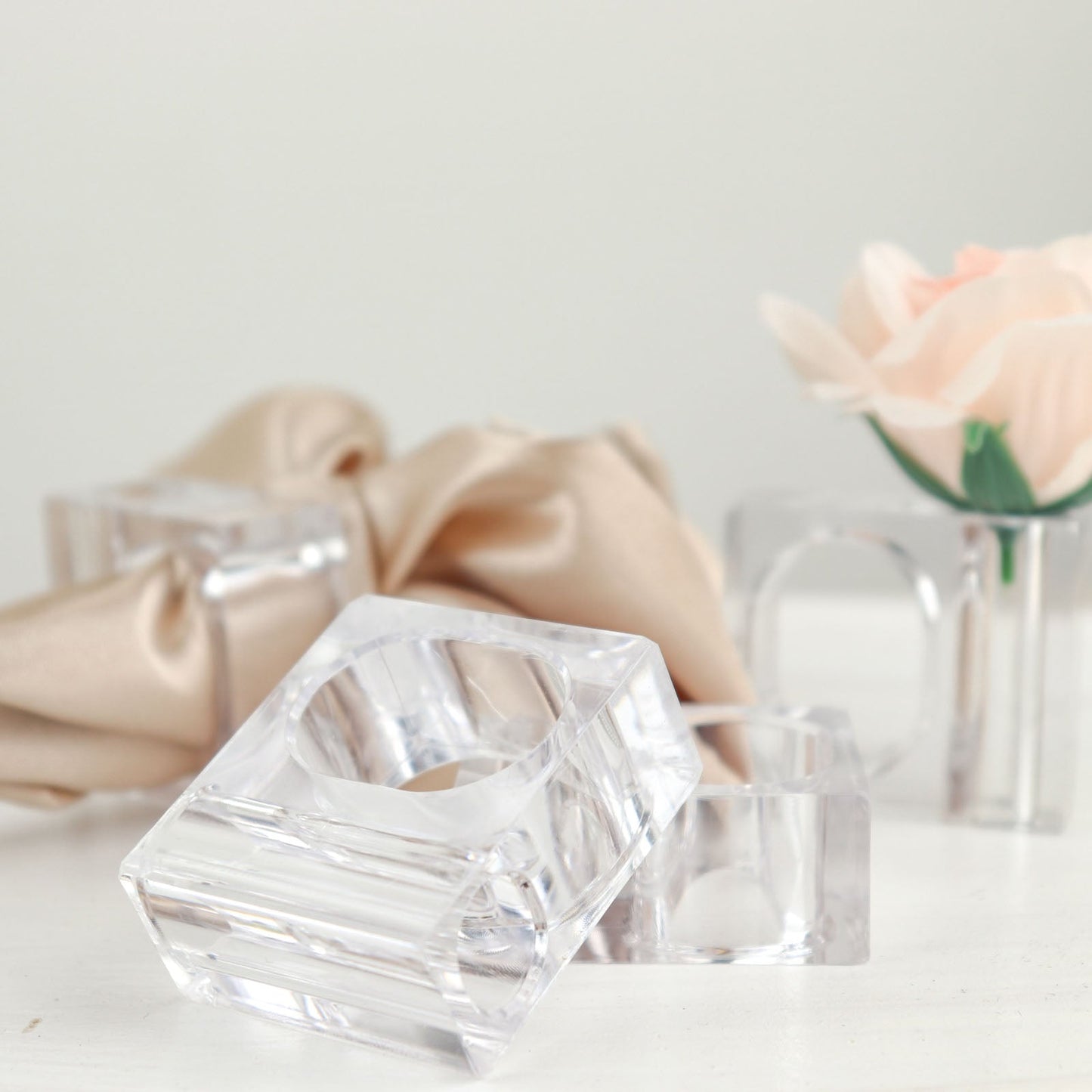 Clear acrylic square mini bud vase napkin rings with a flower.
