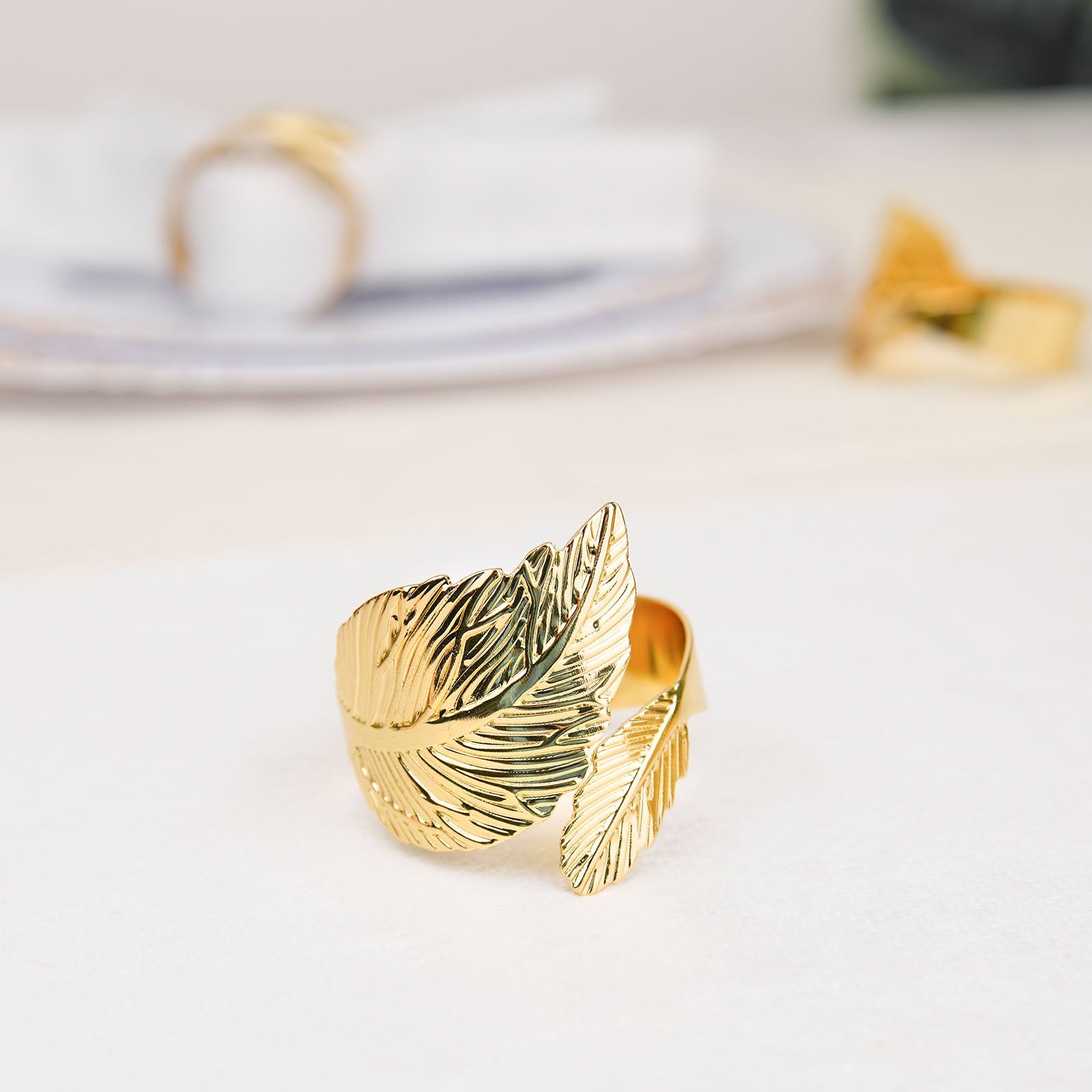 Metallic gold ornate leaf napkin ring on a table setting.