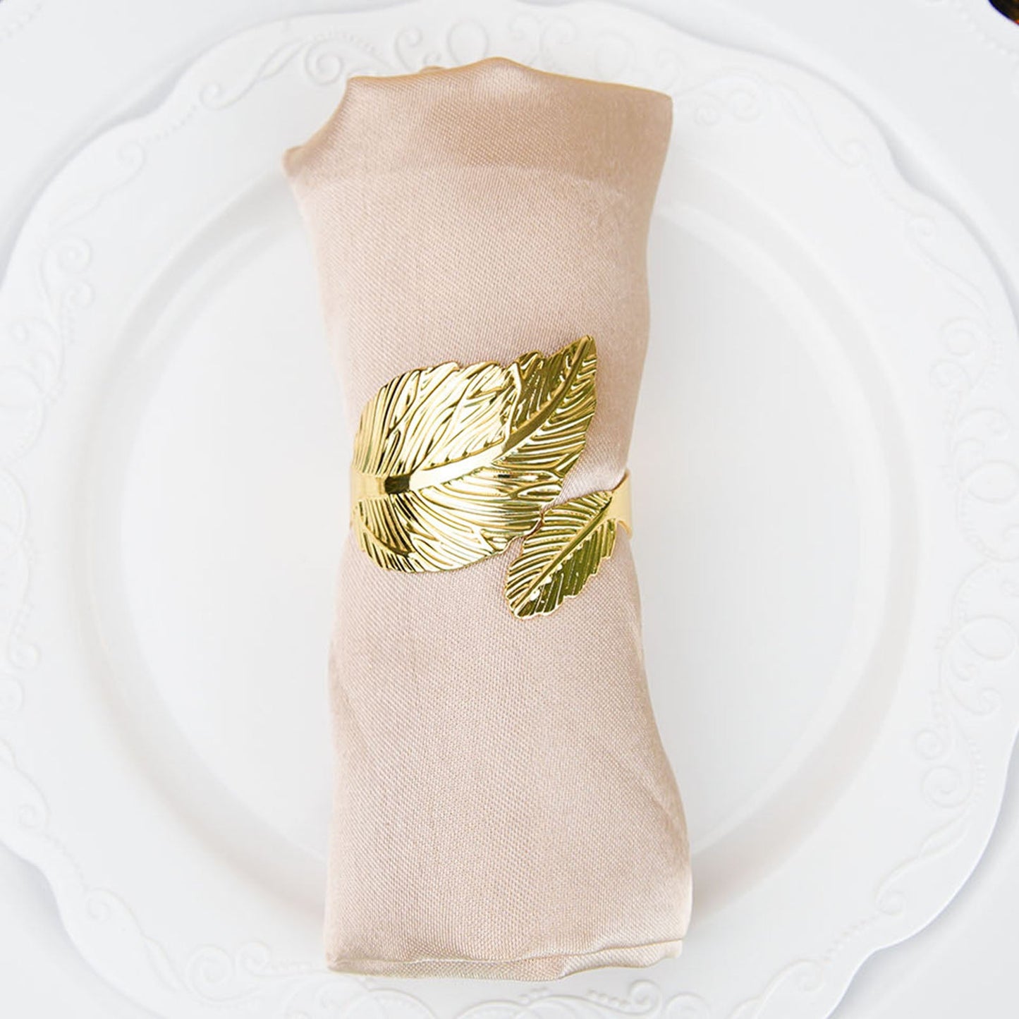 Metallic gold ornate leaf napkin ring on a linen napkin.