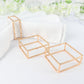 Gold metal hollow square napkin rings on white napkins.