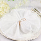 Gold metal hollow square napkin ring holding a white napkin on an elegant plate.