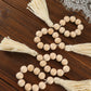 Cream wood bead napkin rings with tassels, rustic farmhouse decor.