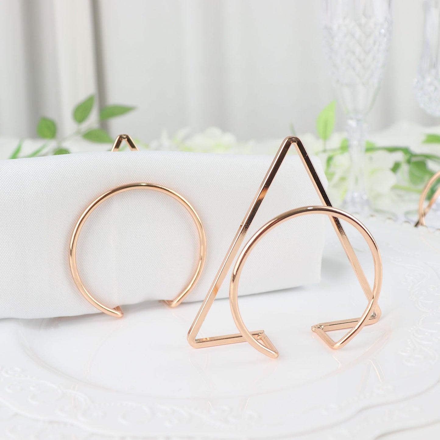 Gold geometric metal napkin rings on a white table setting.