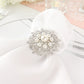 Silver metal napkin ring with pearl and diamond rhinestones on a white napkin.