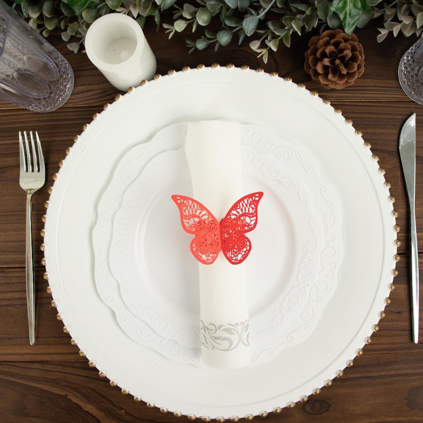 Red shimmery laser cut butterfly napkin ring on a white plate.