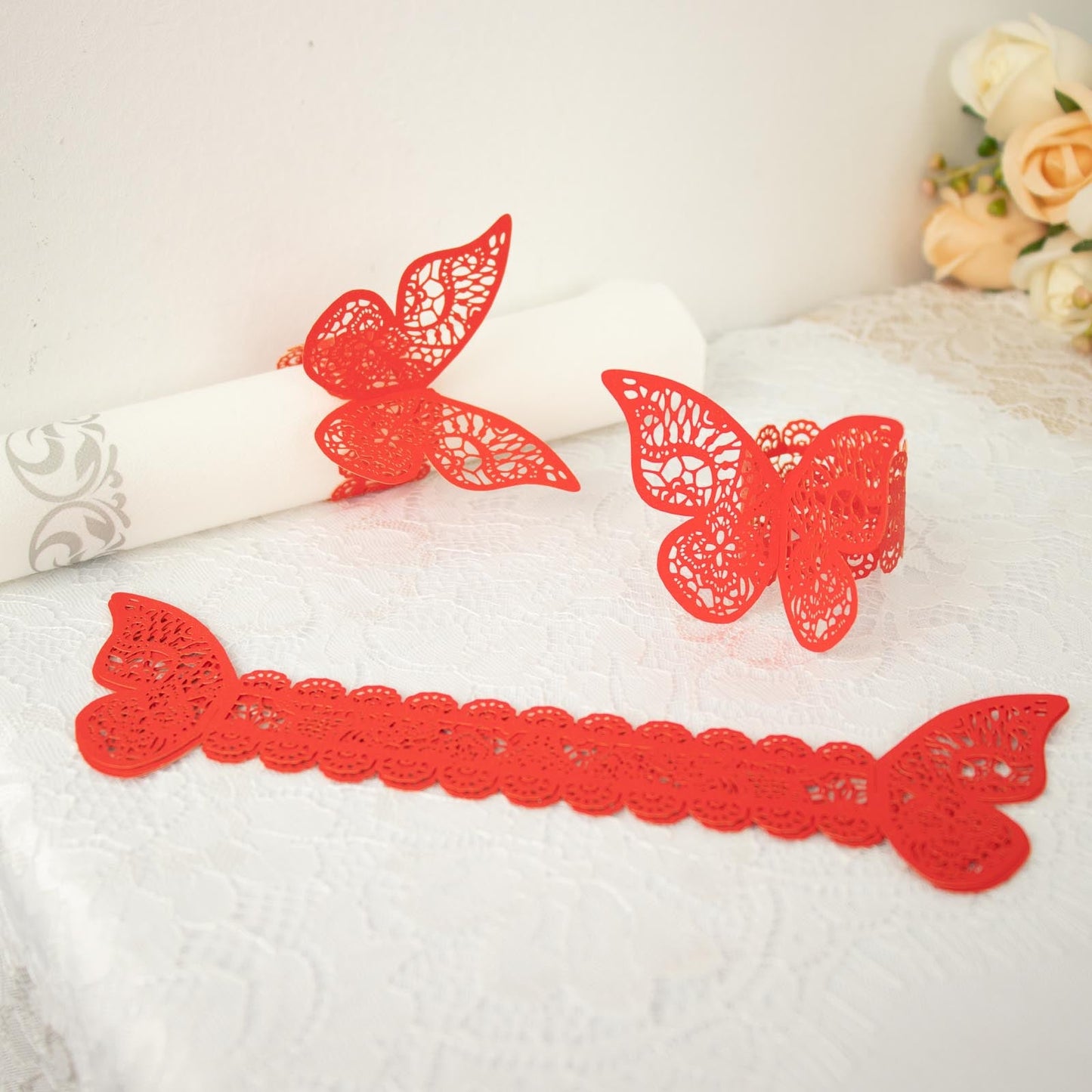 Red shimmery laser cut butterfly napkin rings and chair sash bows.