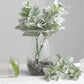 Frosted green artificial lambs ear leaves in a glass vase.