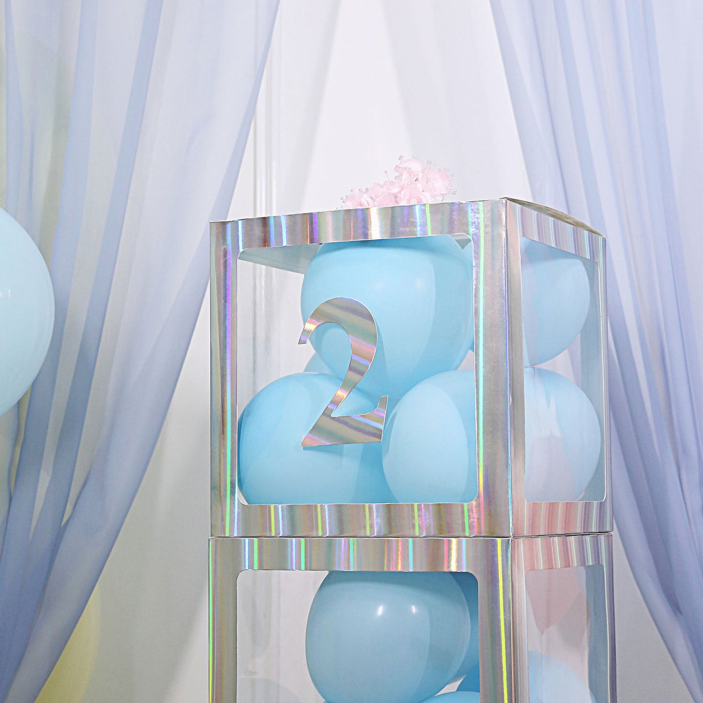Iridescent number 2 sticker on a display with blue balloons.
