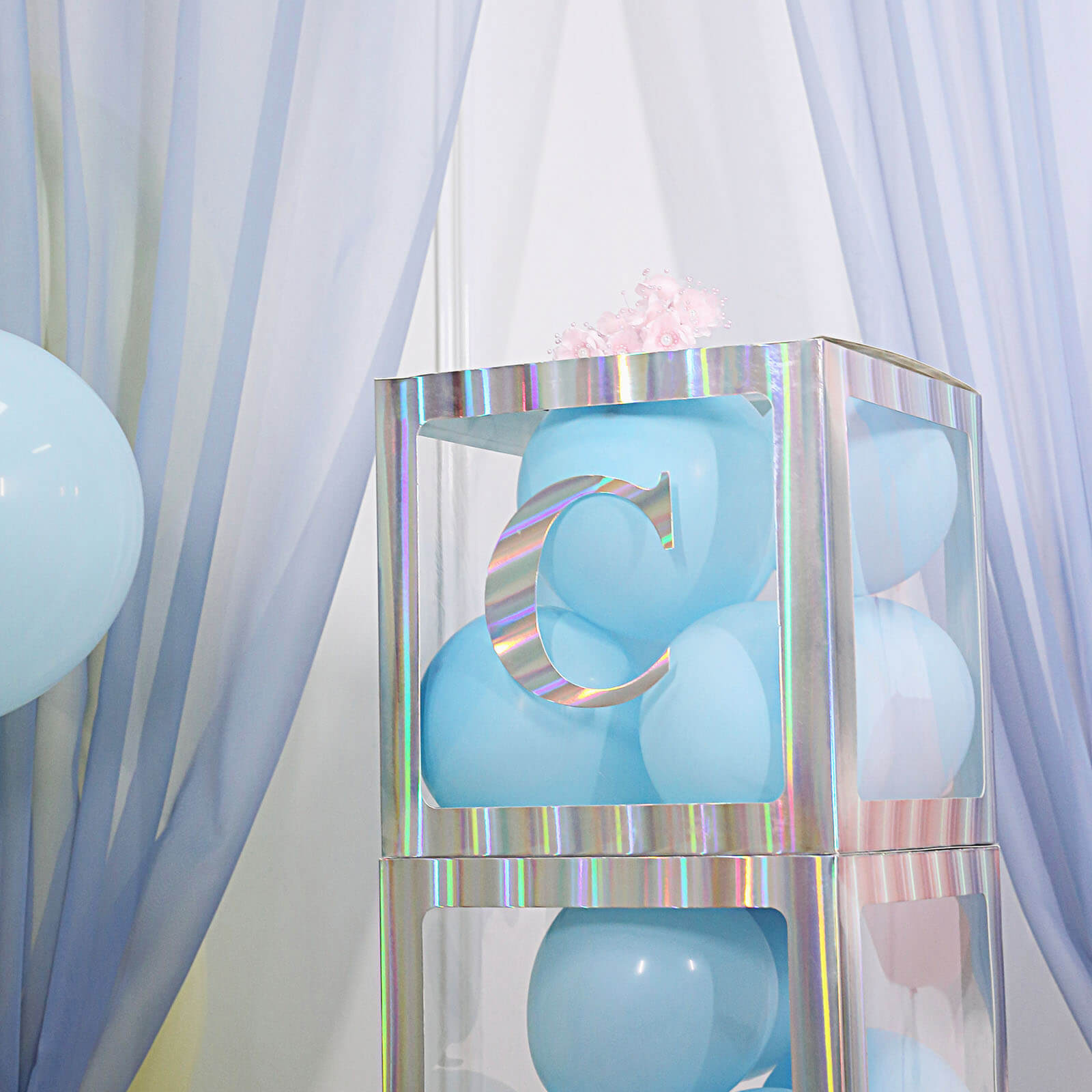 Iridescent letter "C" on a light blue background with balloons.