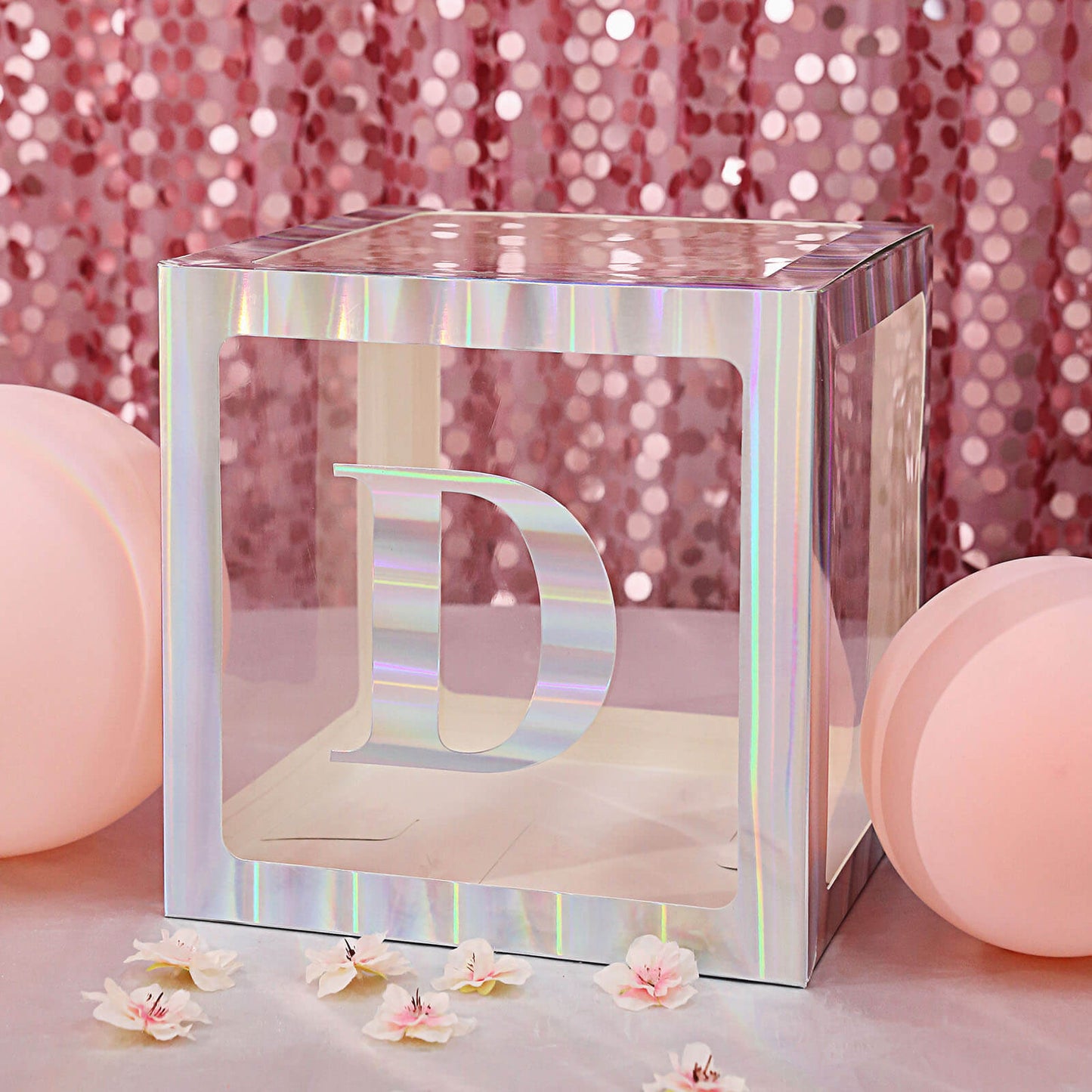 Iridescent letter "D" display box with pink balloons and floral accents.