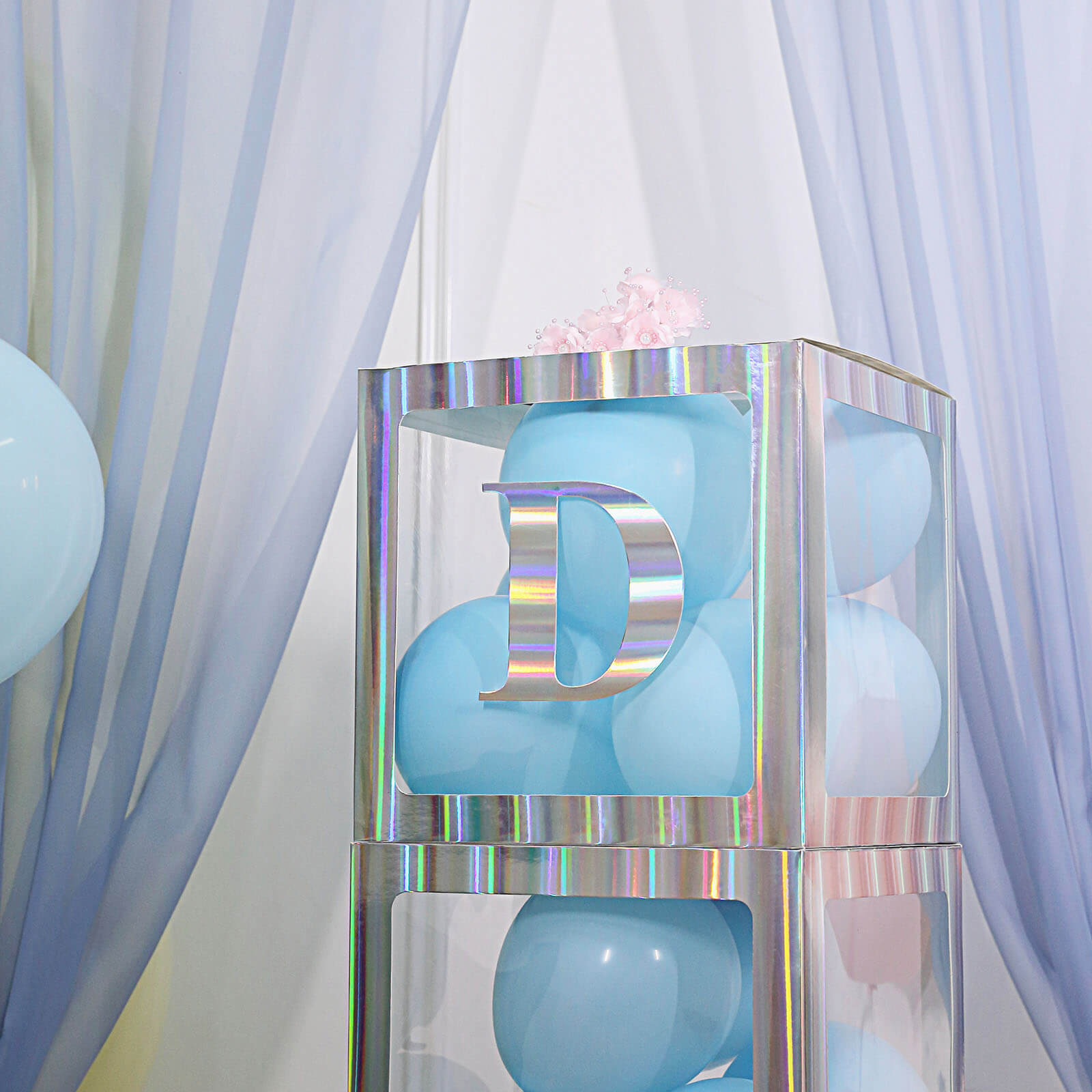 Iridescent alphabet sticker "D" on a display with blue balloons.