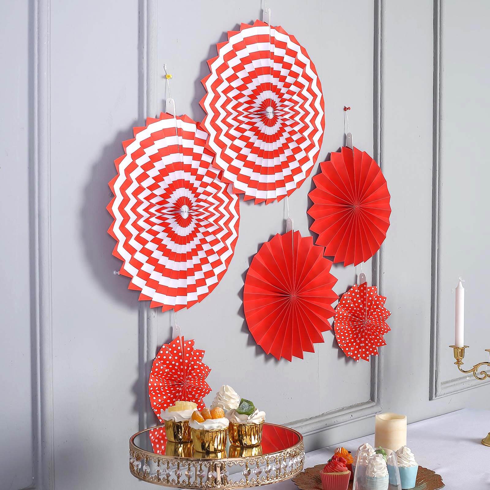 Red hanging paper fan decorations set, featuring pinwheels and backdrops for parties.