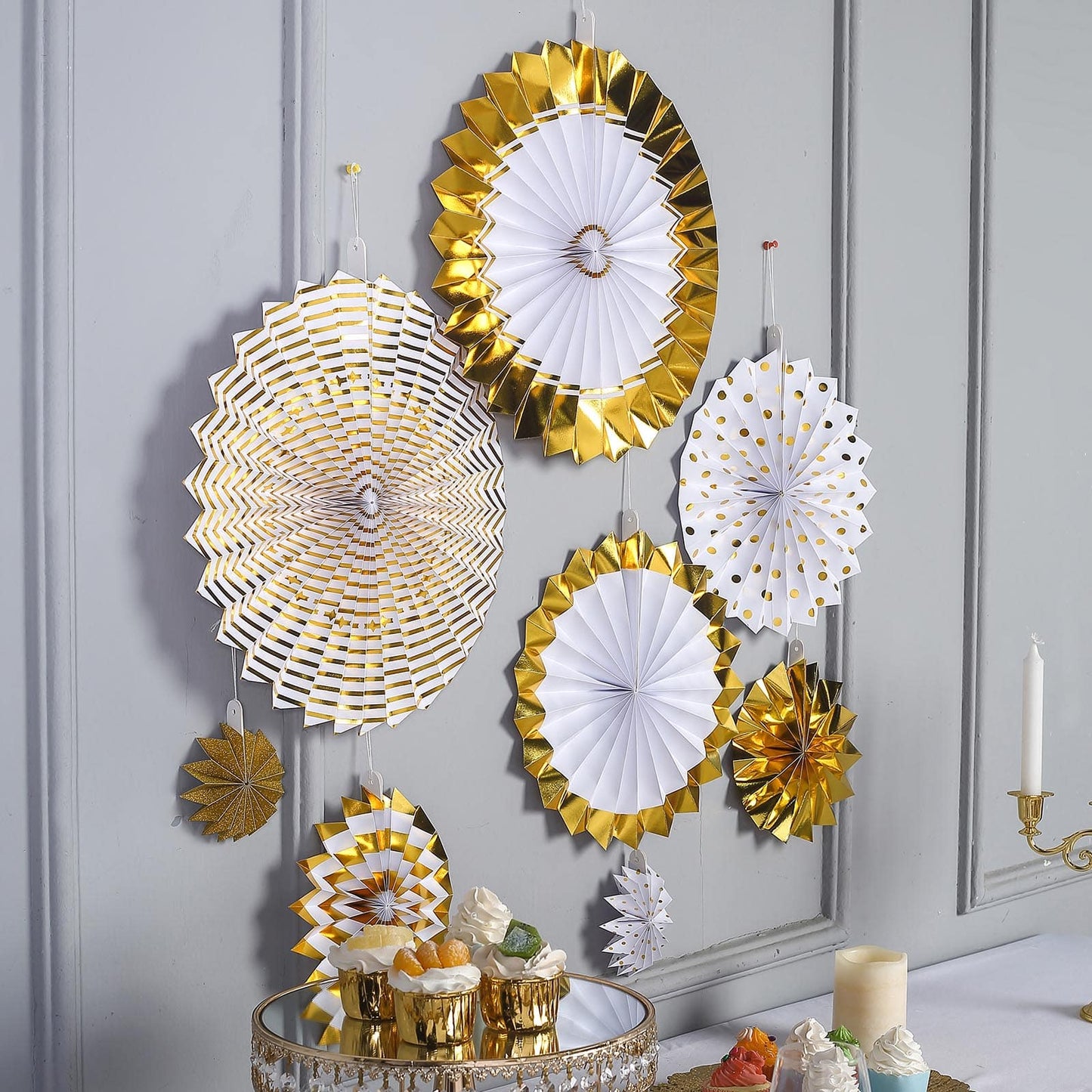 Gold and white hanging paper fan decorations in various sizes.