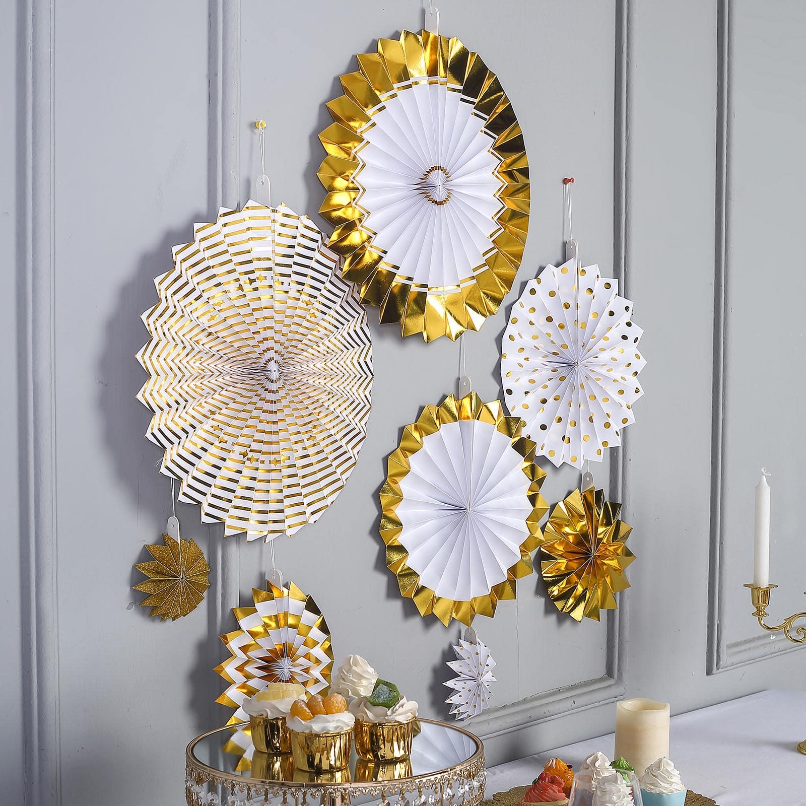 Gold and white hanging paper fan decorations in various sizes.