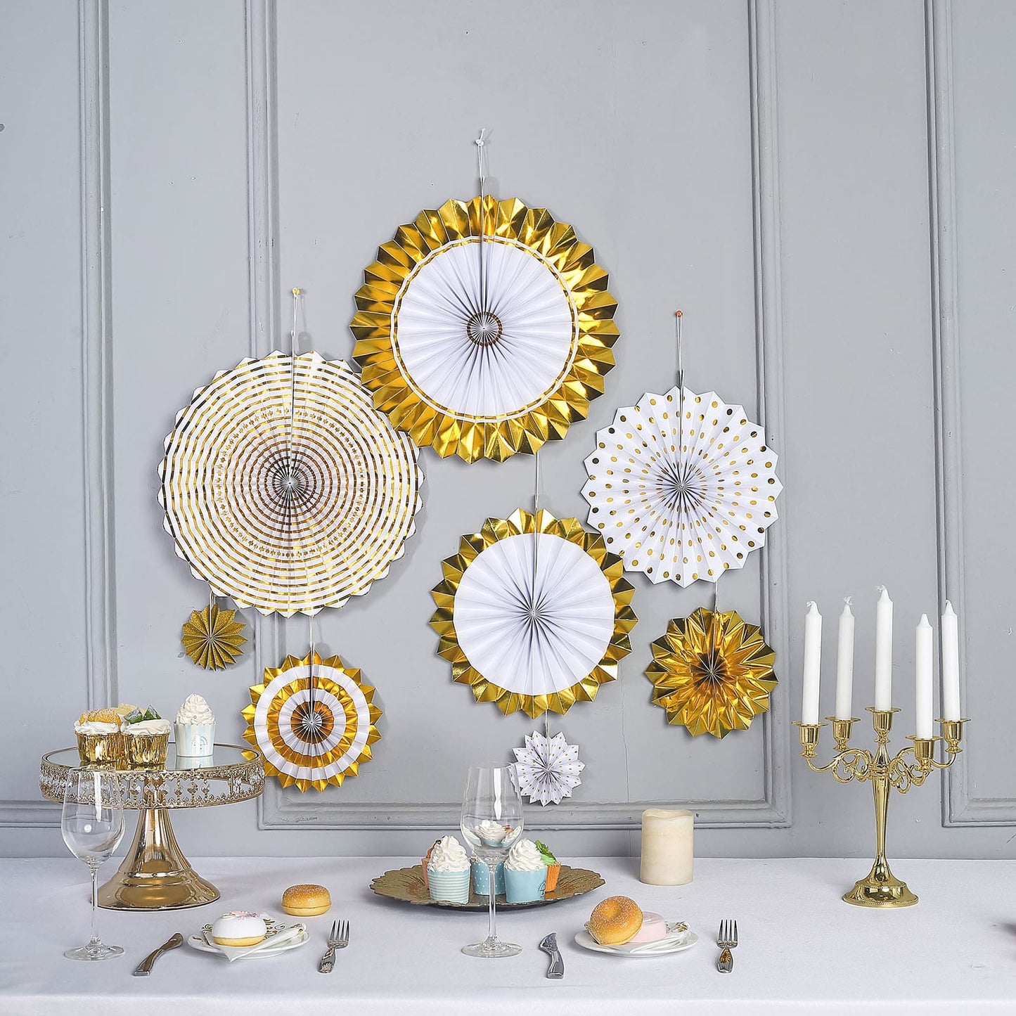 Gold and white hanging paper fan decorations for party backdrop.