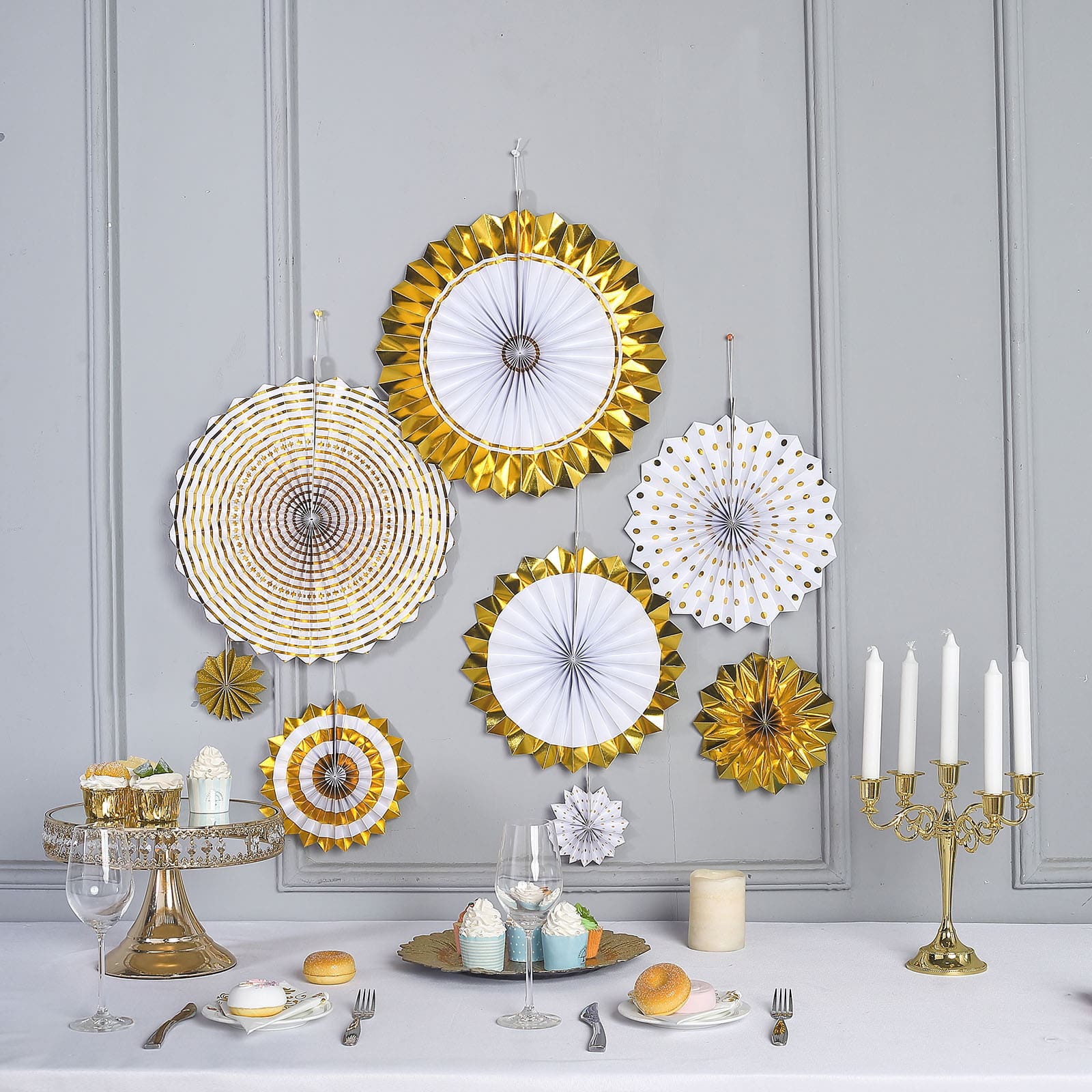 Gold and white hanging paper fan decorations for party backdrop.