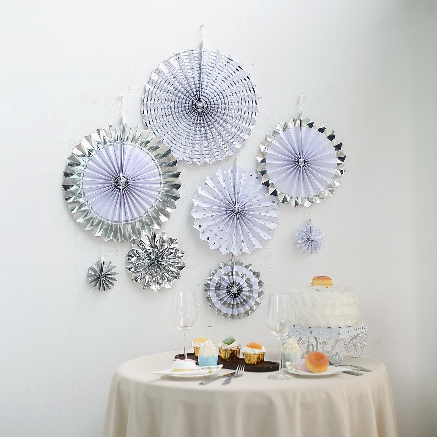 Silver and white hanging paper fan decorations for party backdrop.