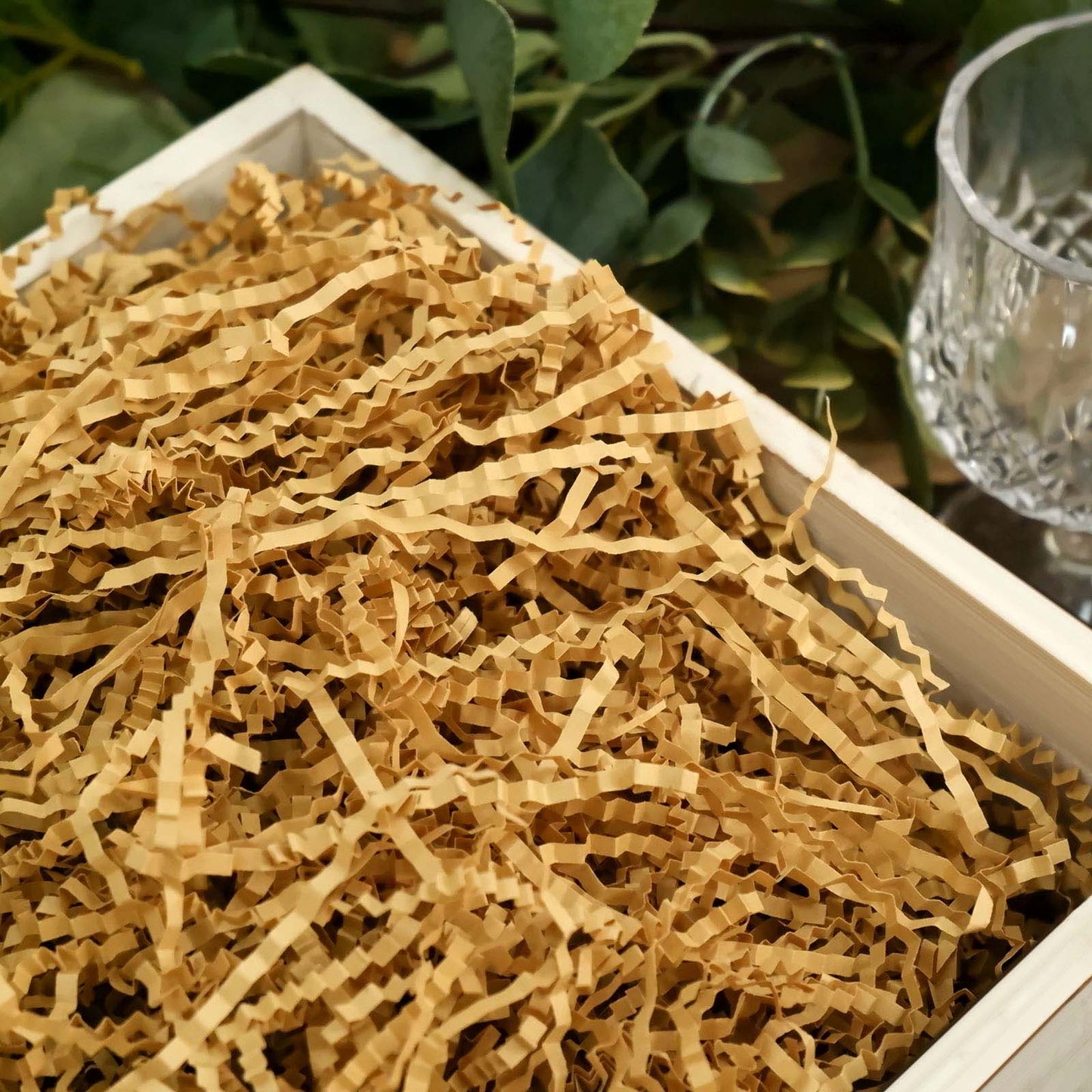 Natural brown paper shred basket filler in a wooden box.
