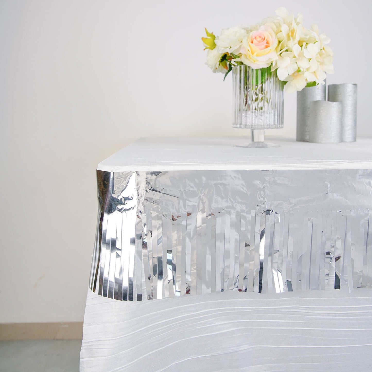 Metallic silver foil tassel fringe backdrop banner on a table with flowers.