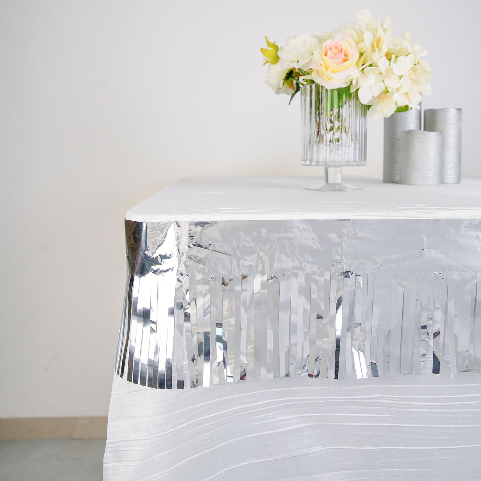 Metallic silver foil tassel fringe backdrop banner on a table with flowers.