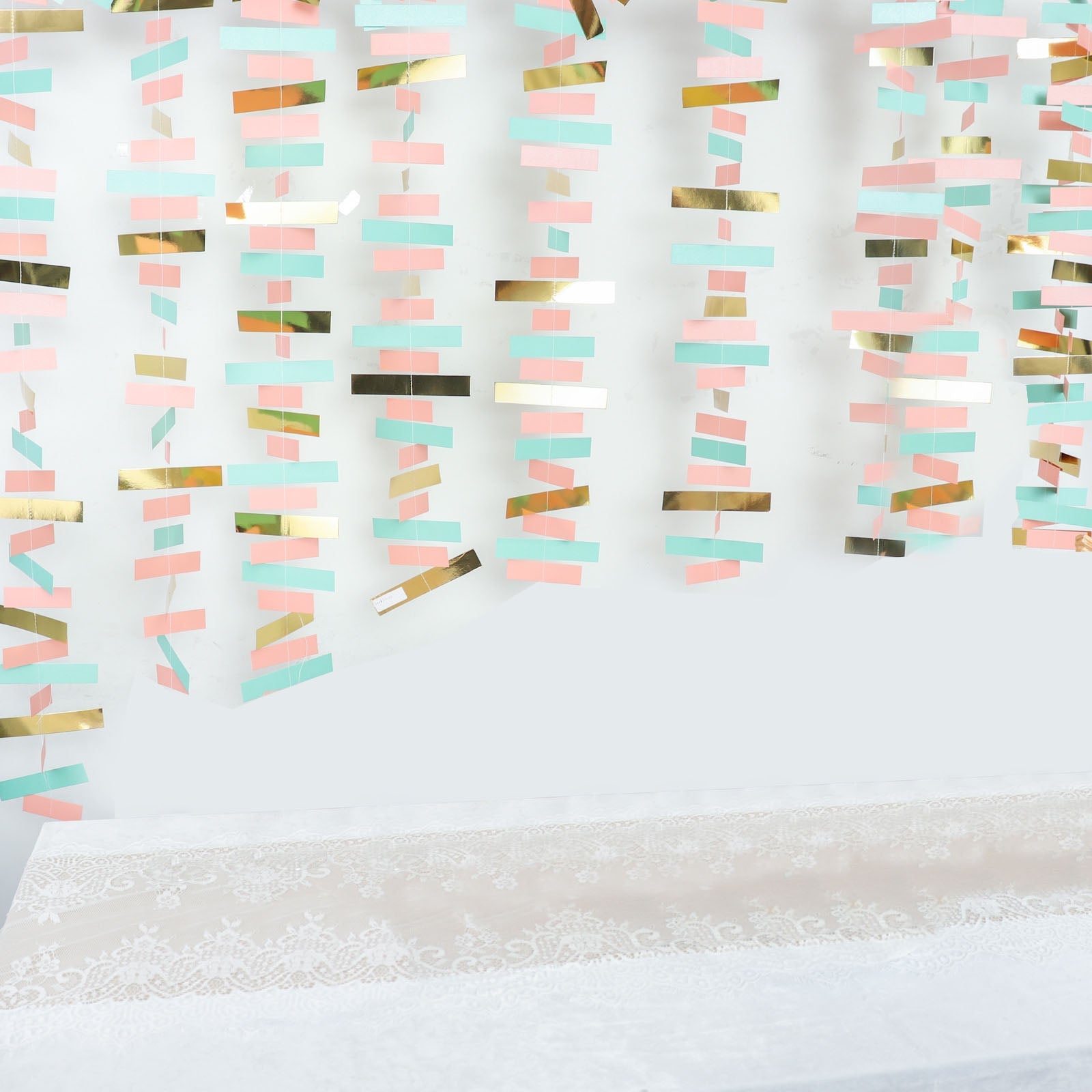 Gold, blush, and turquoise confetti-like paper garland streamer decoration.