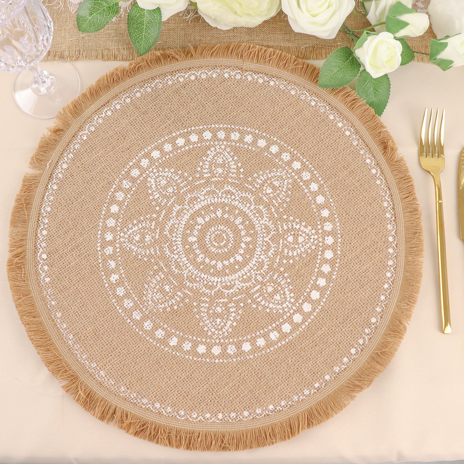 Natural jute round placemat with white embroidery and fringe edges.