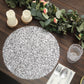Metallic silver round sequin placemat on a wooden dining table.