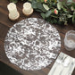 Metallic silver foil round disposable table placemat on a rustic wooden table.