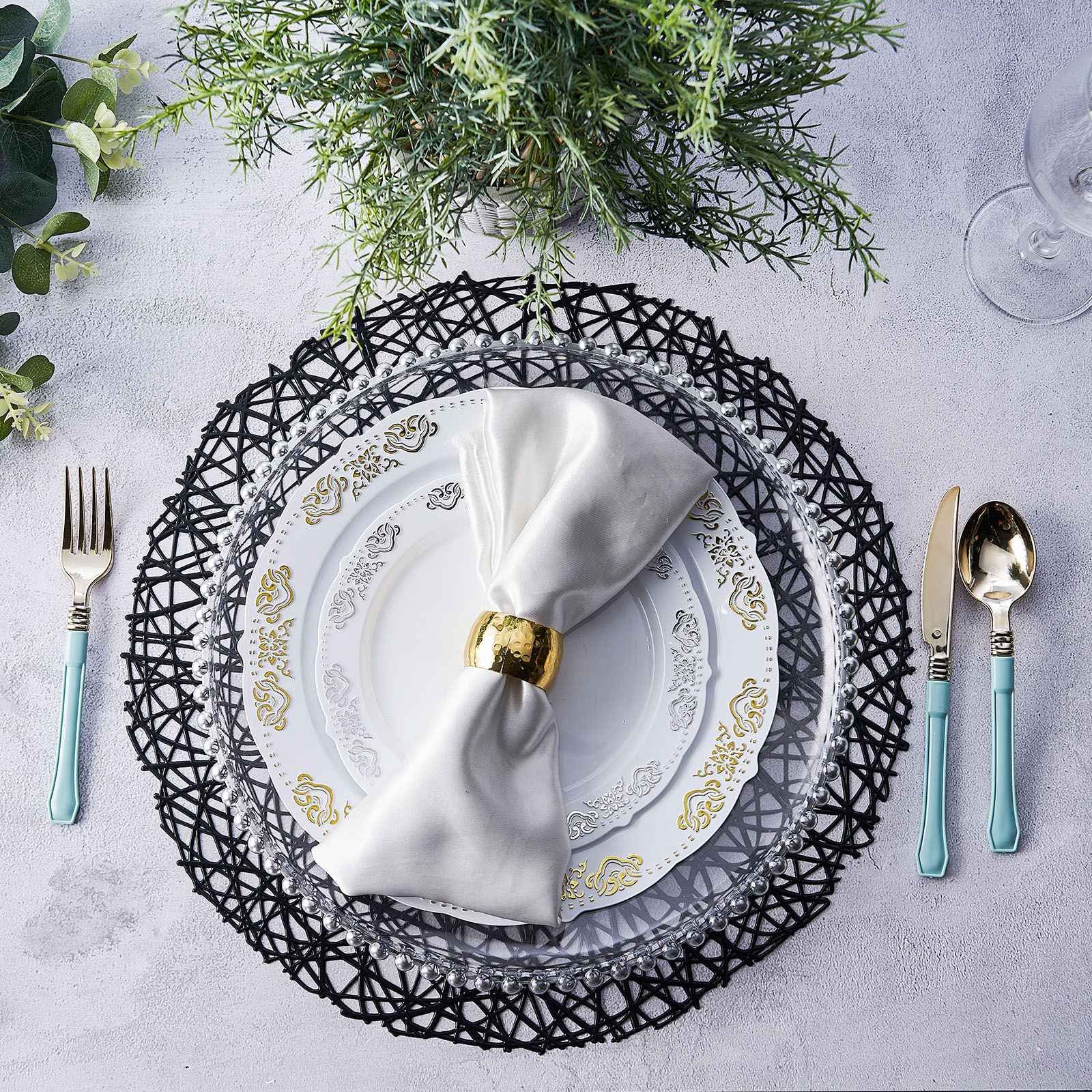 Black vinyl placemats on a table setting with white plates and silver utensils.