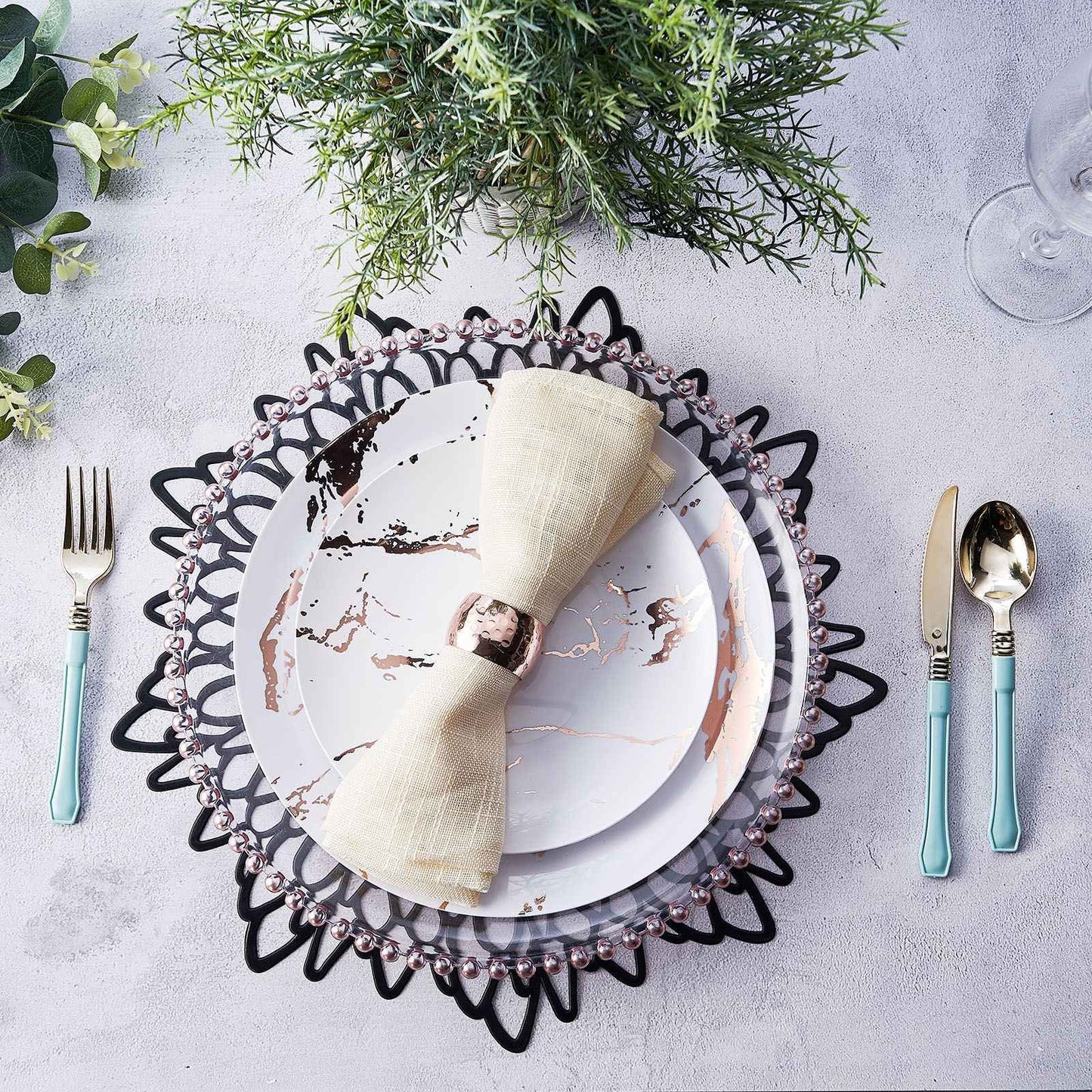 Black vinyl placemats with decorative floral design on a dining table setting.