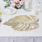 Gold monstera leaf placemat on a dining table with floral decor.