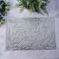 Silver metallic placemat with wheat design on a light surface.
