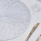 Silver metallic round placemat with a spiked design on a light table setting.