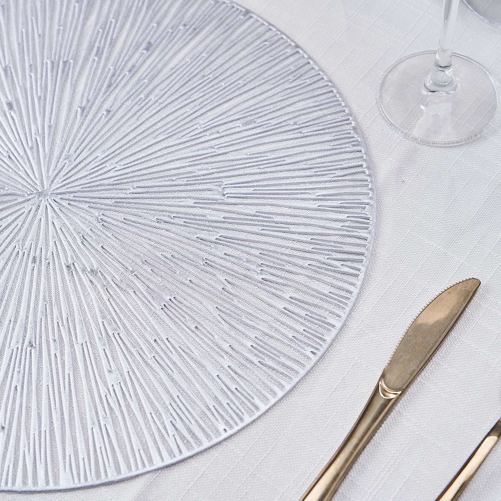 Silver metallic round placemat with a spiked design on a light table setting.