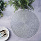 Silver metallic round placemat with textured spiked design on a table.