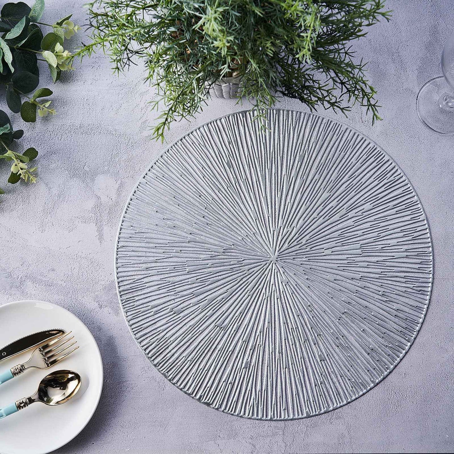 Silver metallic round placemat with textured spiked design on a table.