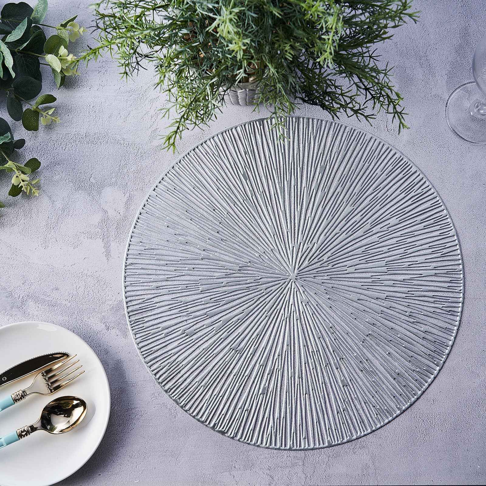 Silver metallic round placemat with textured spiked design on a table.