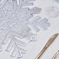 Silver metallic vinyl placemat with snowflake design on a table setting.