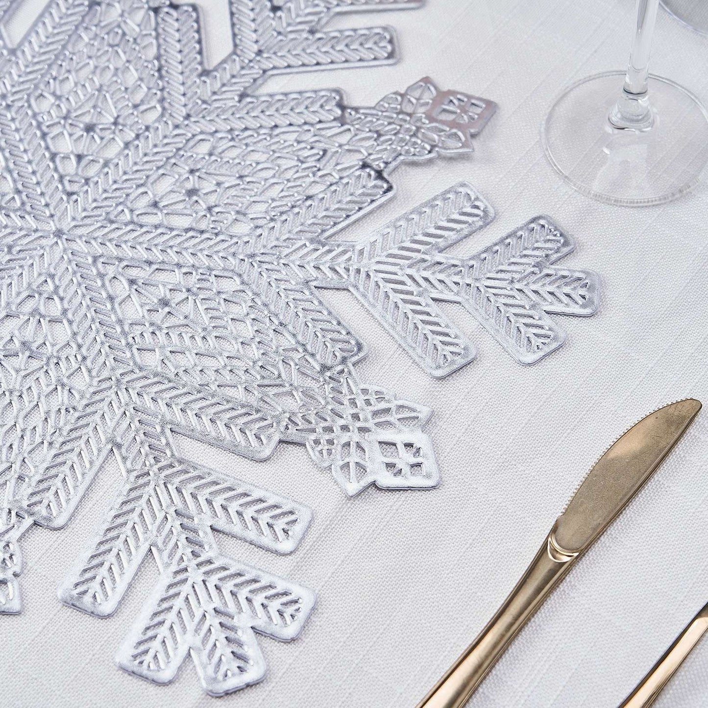 Silver metallic vinyl placemat with snowflake design on a table setting.
